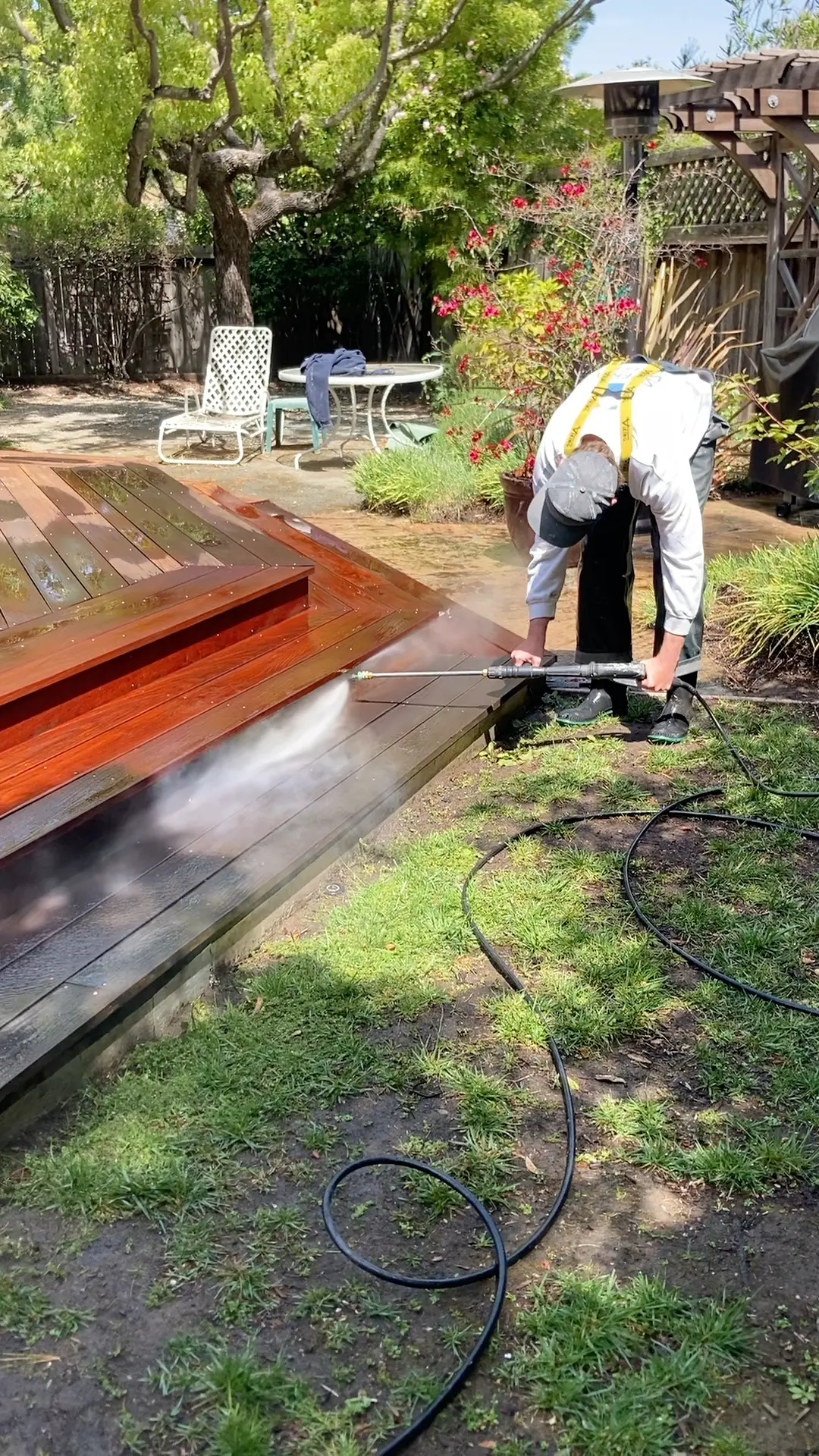 Person pressure washing outdoor wooden deck.