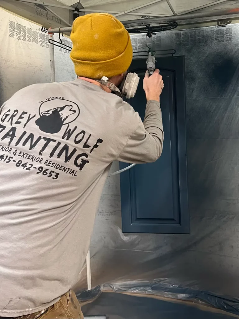 Painter spray-painting a blue door.