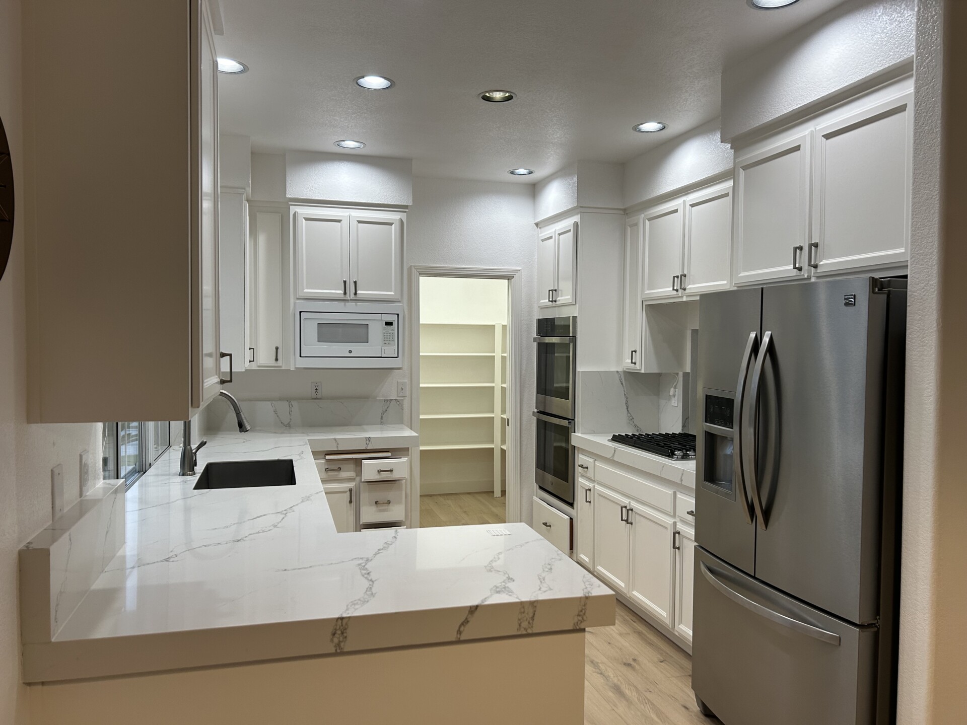 Modern kitchen interior with white cabinets and stainless appliances.