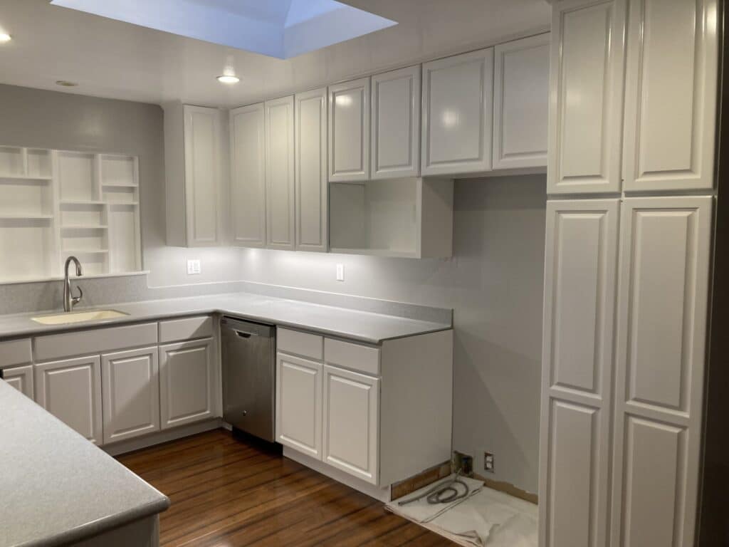 Modern kitchen with white cabinets and hardwood flooring.