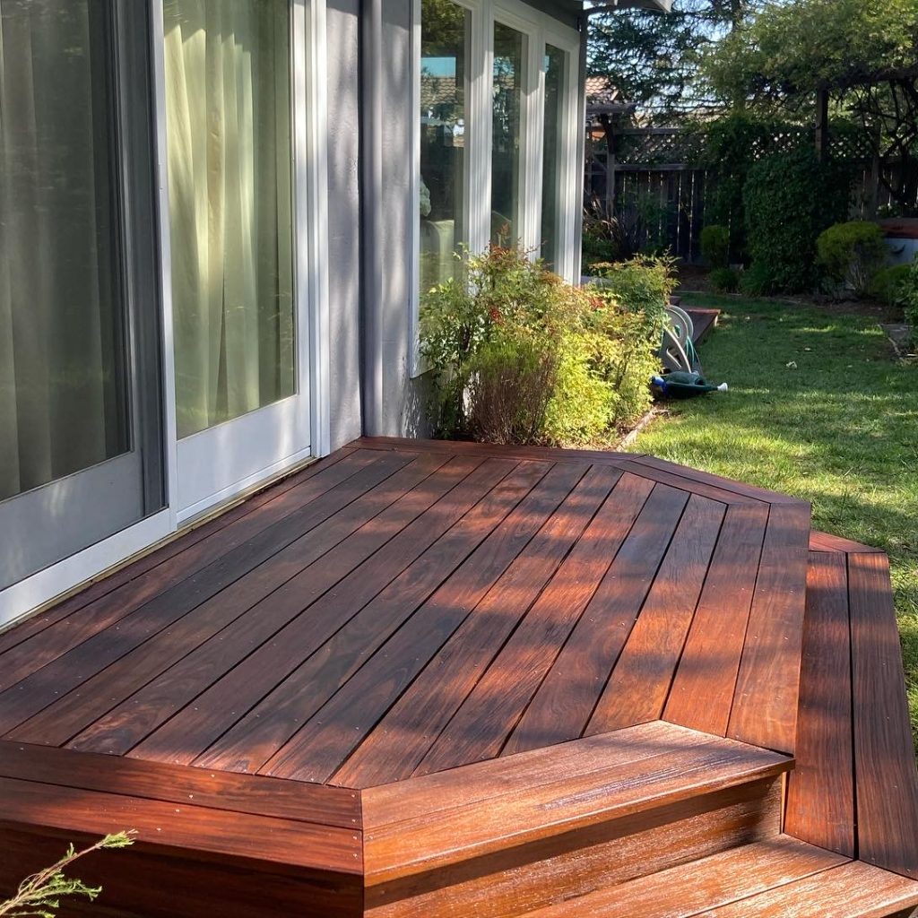 Wooden backyard deck with steps near sliding glass door.