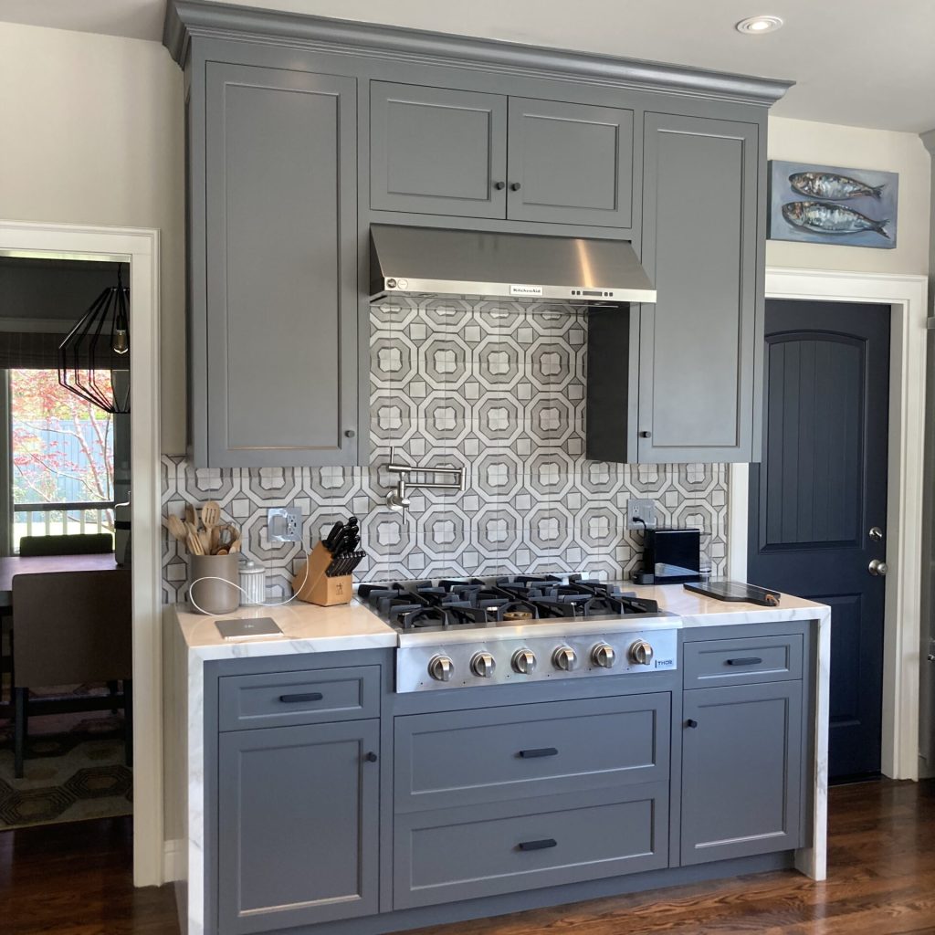 Modern kitchen with blue-gray cabinets and patterned backsplash.