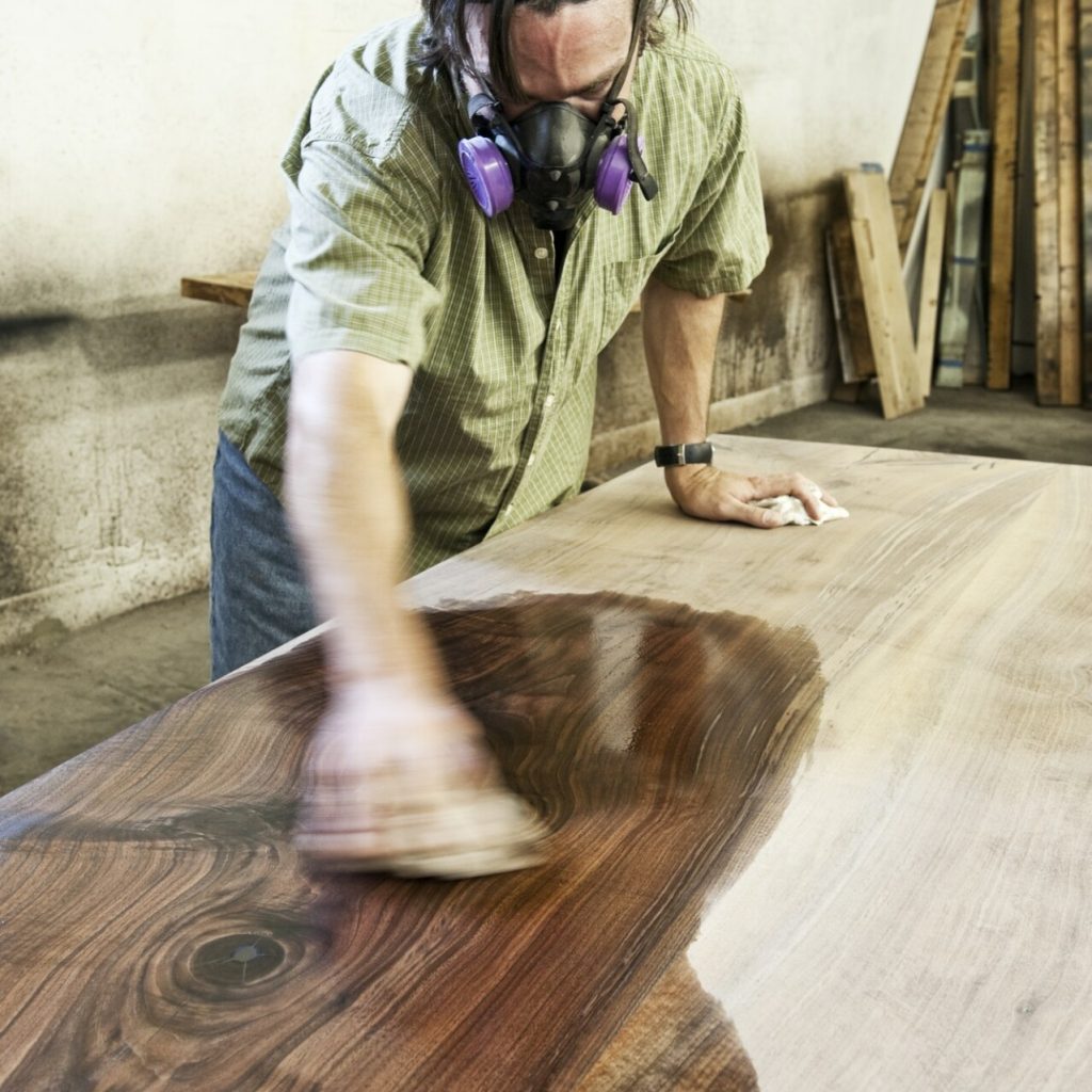 Man staining wood in workshop