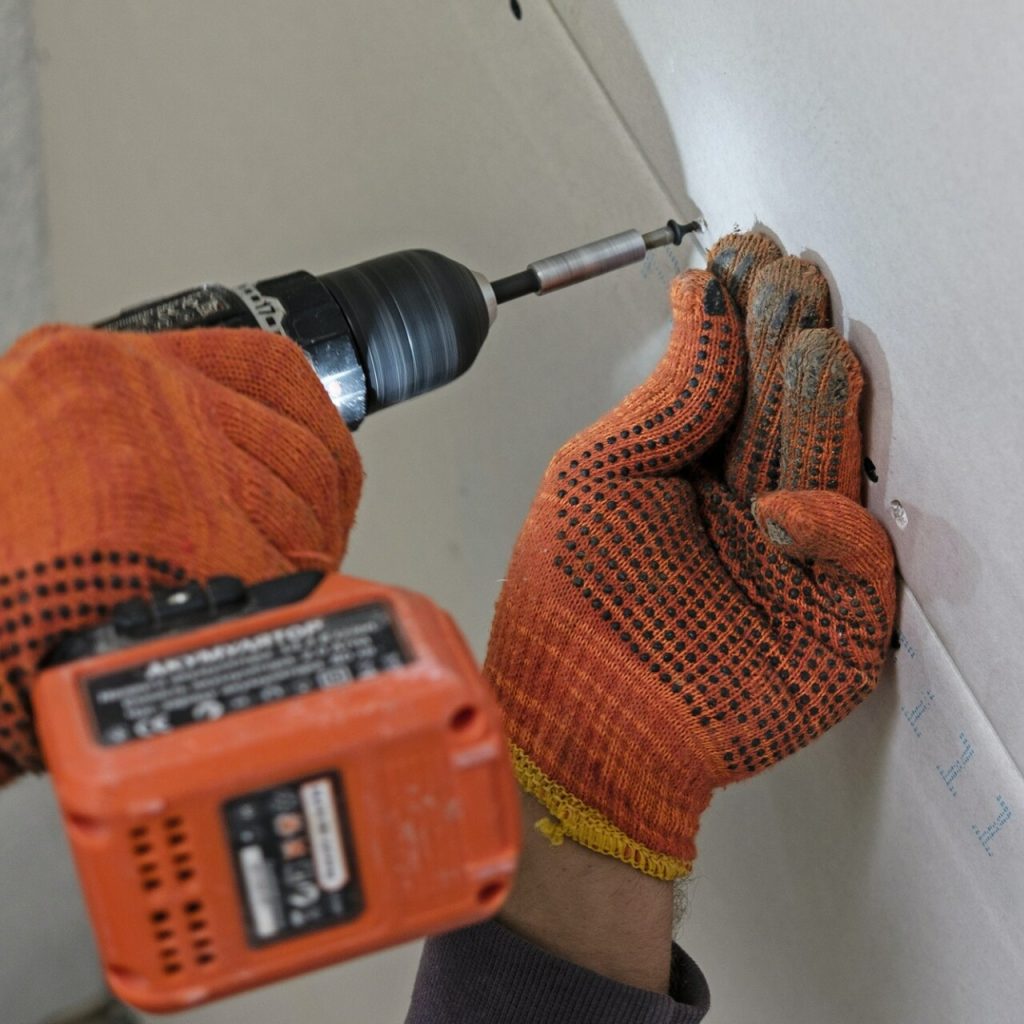 Person using drill on drywall.
