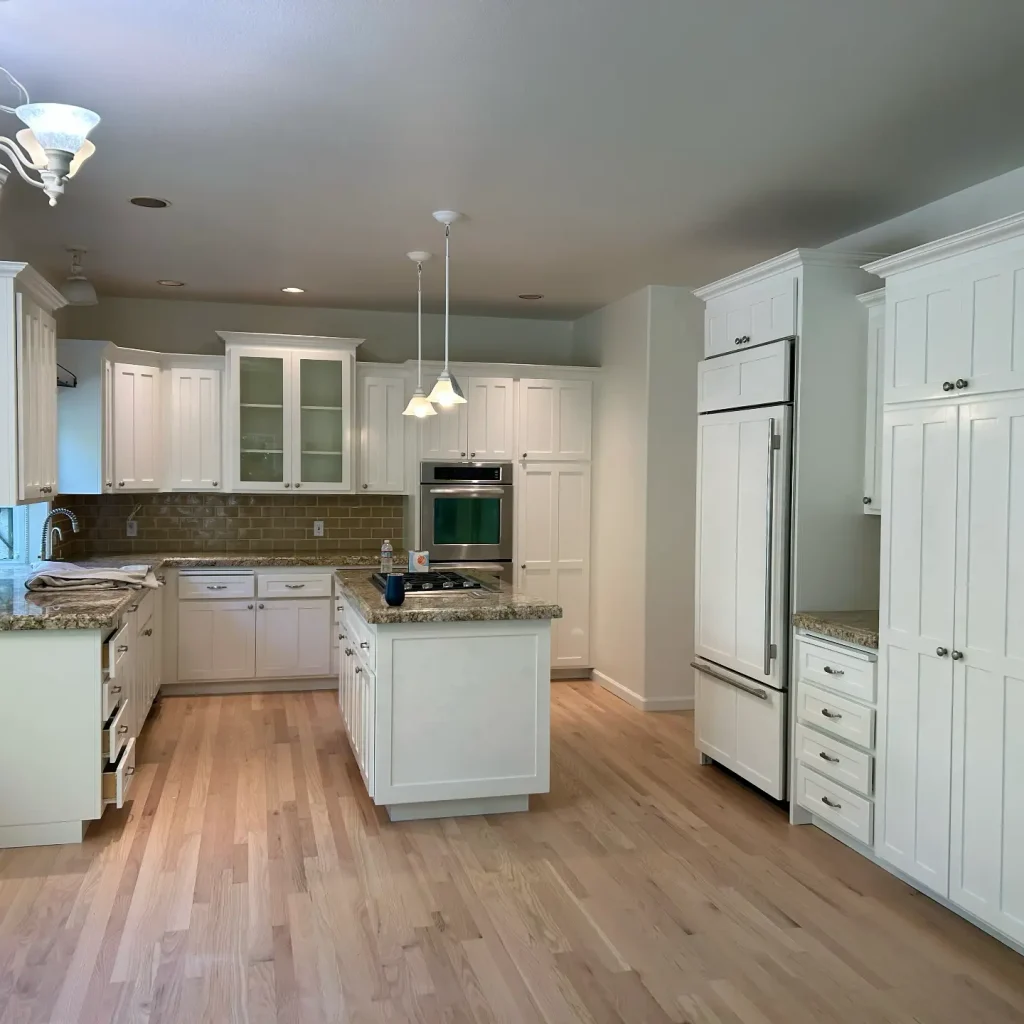 Modern kitchen interior with white cabinets and appliances.