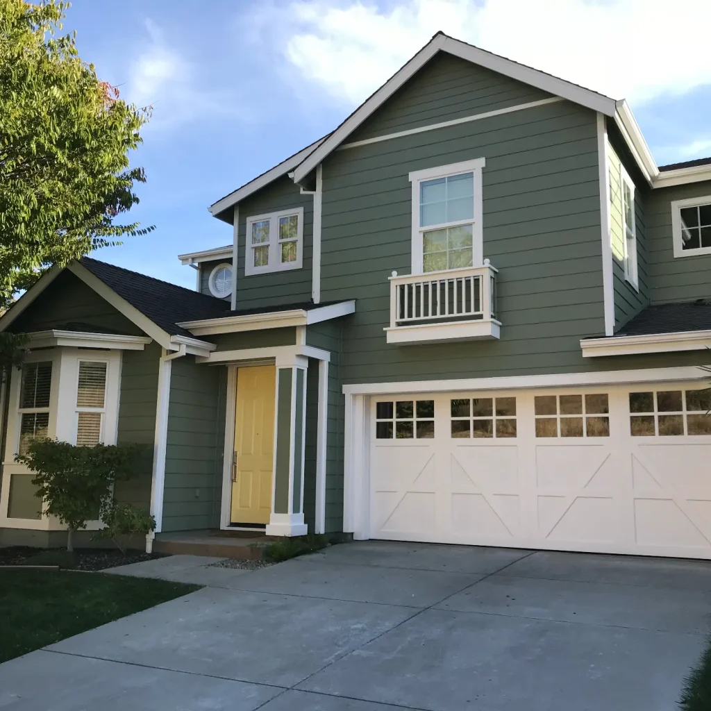 Green two-story suburban house with garage.