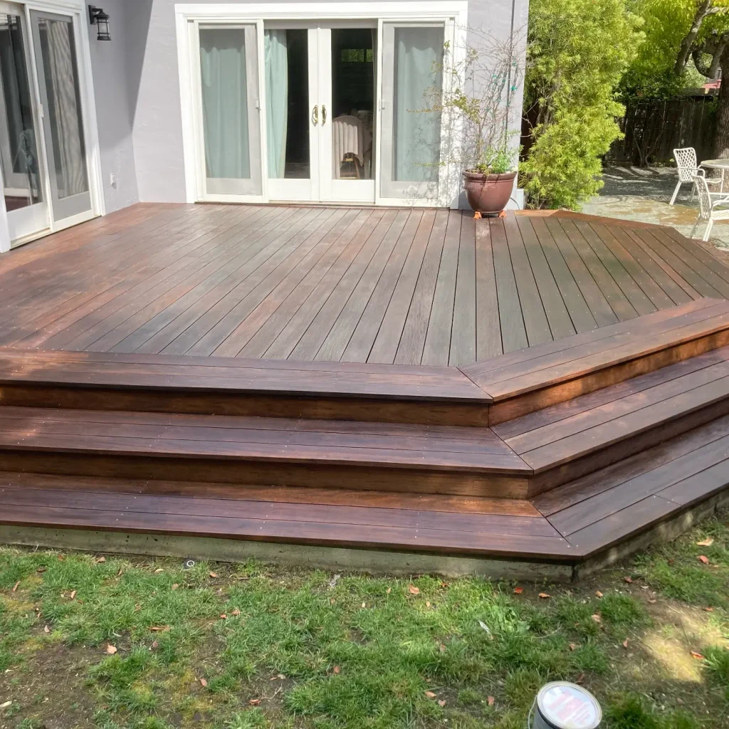 Wooden backyard deck with steps and patio furniture.