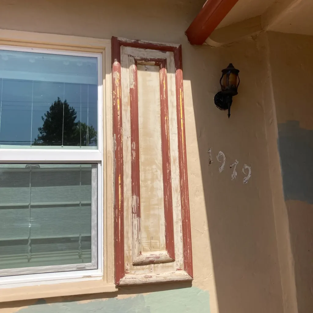 Window with peeling paint and wall-mounted lantern.