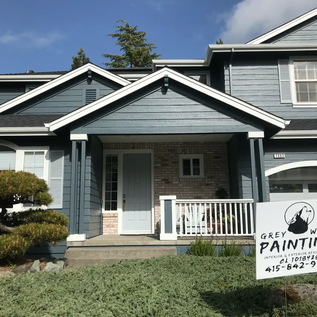 Painted exterior. Blue two-story house with painting service sign.