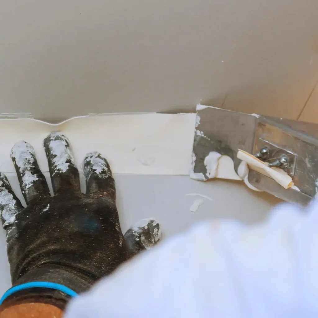 Person applying joint compound for drywall repair.