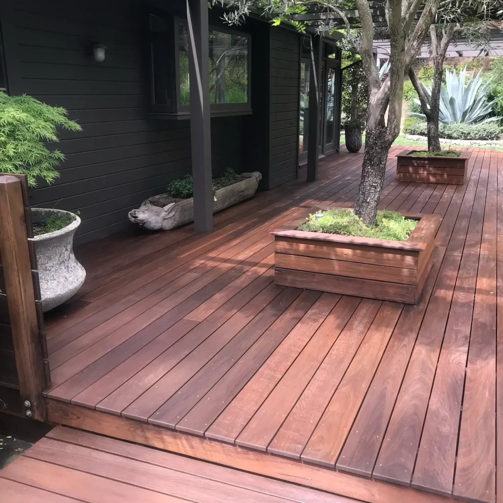 Wooden deck pathway at modern house with greenery.