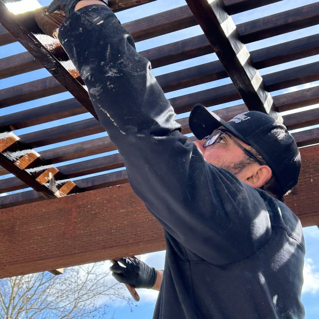 Man working on wooden pergola outdoors.
