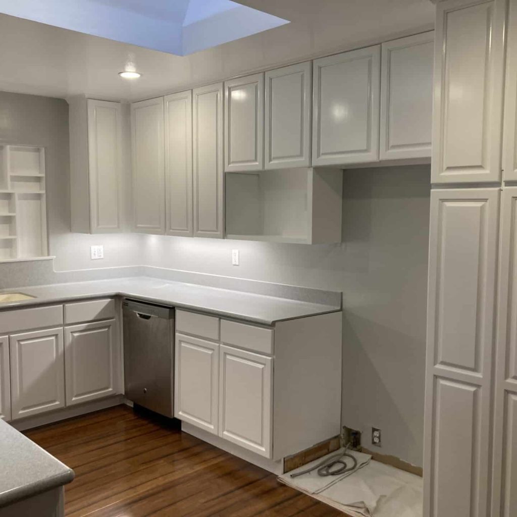 Modern kitchen with white cabinets and hardwood flooring.