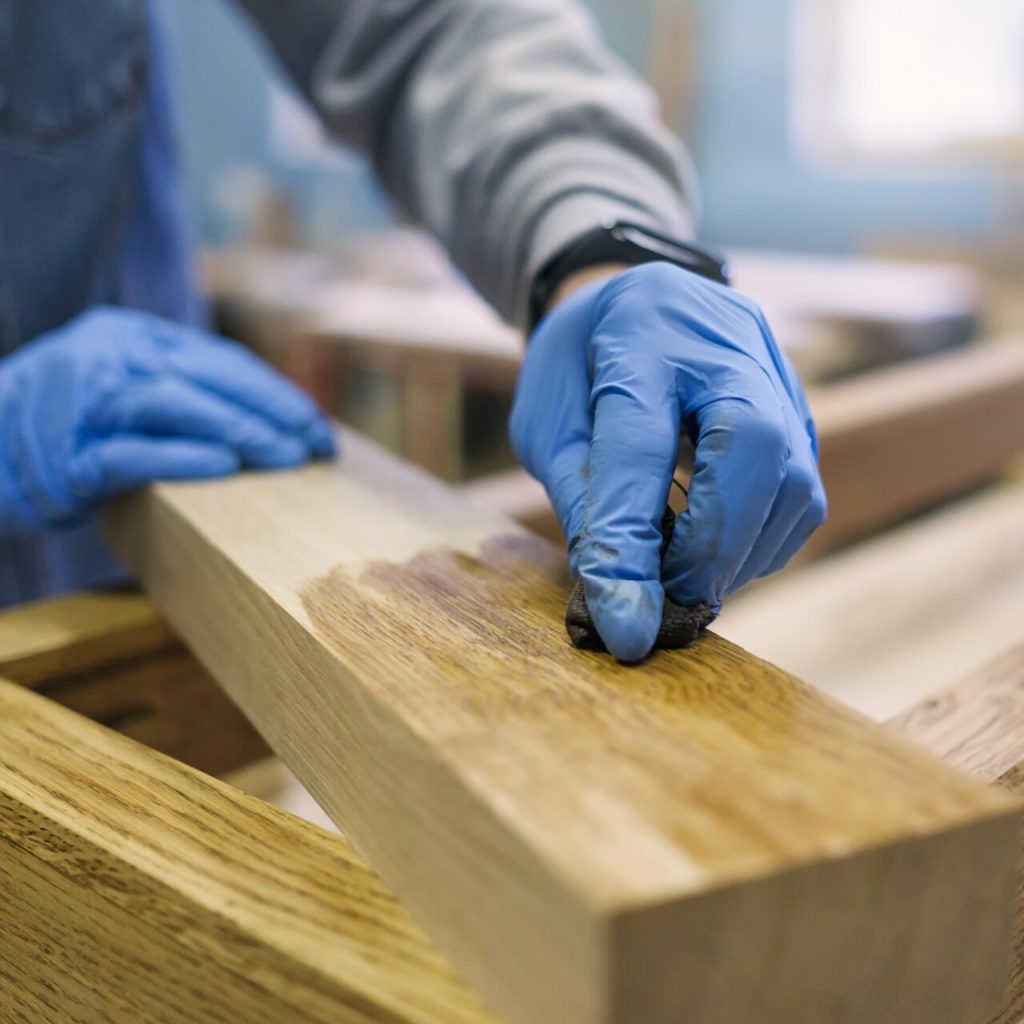 Person staining wood in carpentry workshop.