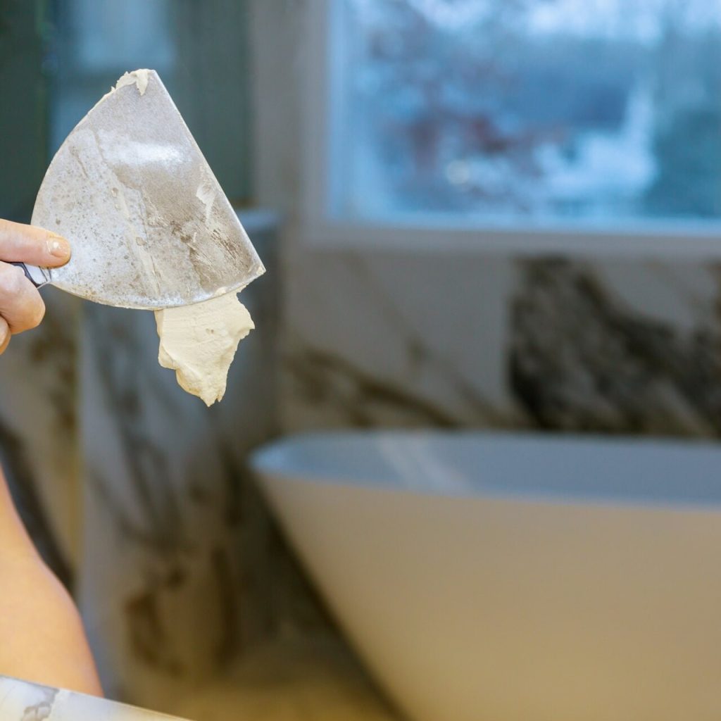 Person applying plaster with trowel indoors.